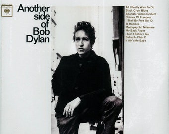 May include: A black and white photo of Bob Dylan on the cover of his album "Another Side of Bob Dylan". The album cover features the title of the album and a list of songs included on the album.