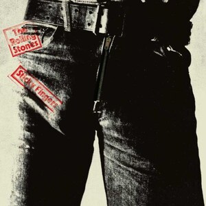 May include: A black and white graphic print of denim jeans featuring a prominent metal zipper fly and a wide leather belt. The text The Rolling Stones is printed in a red rectangular box, and the text Sticky Fingers is in a second red box.