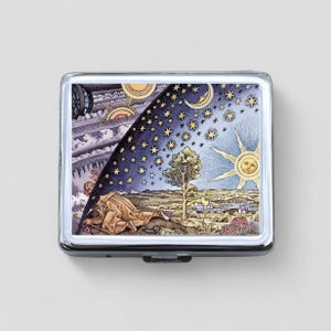 May include: A silver metal cigarette case with a colorful illustration of a man looking up at a celestial dome with stars, a sun, and a moon. The illustration is reminiscent of a medieval depiction of the universe.