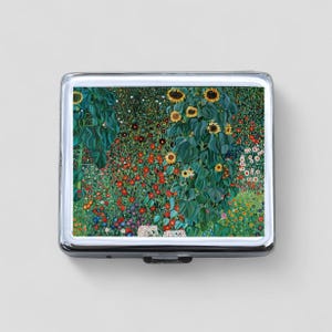 May include: A silver metal cigarette case with a colorful image of a field of sunflowers and other flowers. The image is a painting with a pointillist style.