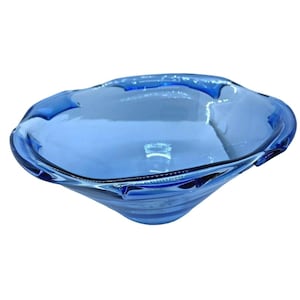 May include: A blue glass bowl with a wavy rim. The bowl is a light, transparent blue and has a rounded, organic shape. The glass has a smooth, glossy finish.