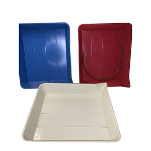 May include: Three plastic trays for developing photographic prints. One tray is blue, one is red, and one is white.