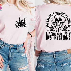 Op de afbeelding: Roze T-shirt met een zwarte schedelprint en de tekst "You couldn't handle me even if I come with the instructions".
