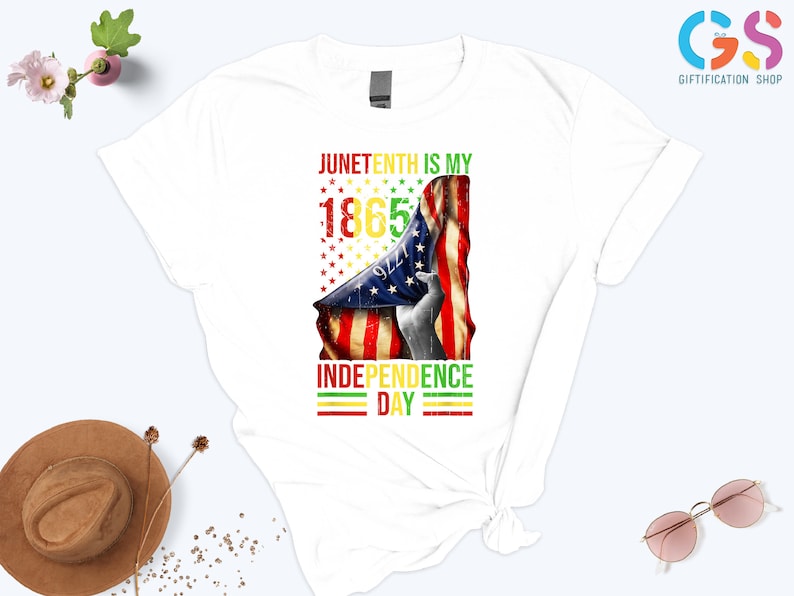 Puede incluir: Camiseta blanca con un dise&ntilde;o gr&aacute;fico que celebra el Juneteenth. El dise&ntilde;o incluye el texto "Juneteenth is my Independence Day 1865" con una bandera americana y estrellas. La camiseta es una prenda informal.