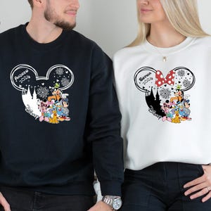 Pode incluir: Camisolas pretas e brancas com um design de cabe&ccedil;a do Mickey Mouse com personagens da Disney. A camisola preta tem impresso "Andrew 2026", enquanto a camisola branca tem "Sophia 2026". Ambas t&ecirc;m a palavra "Disney" impressa.