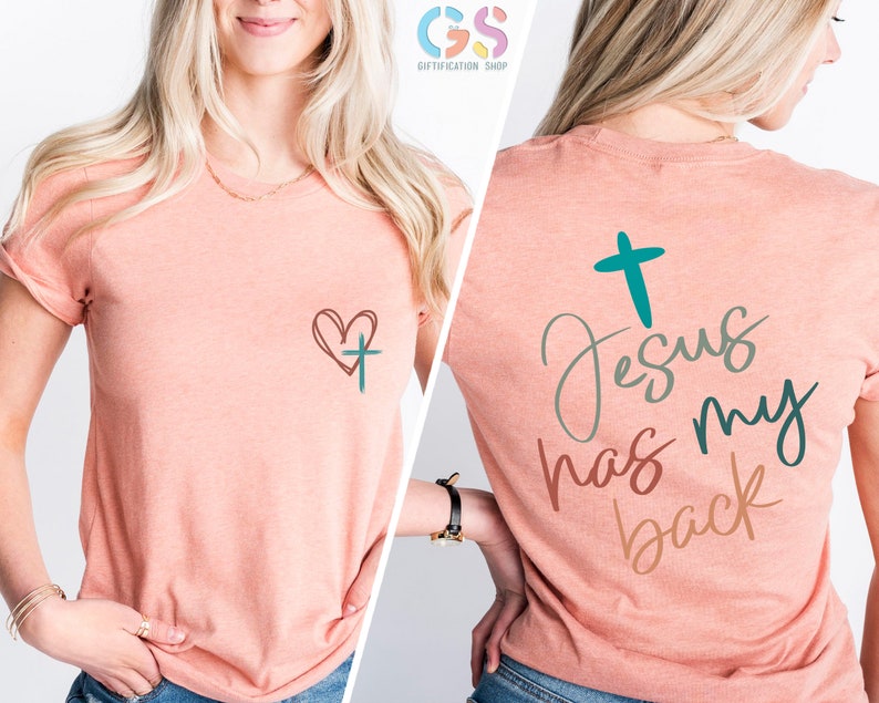 May include: A peach-colored t-shirt with a heart and cross design on the front and the text "Jesus has my back" with a cross on the back.