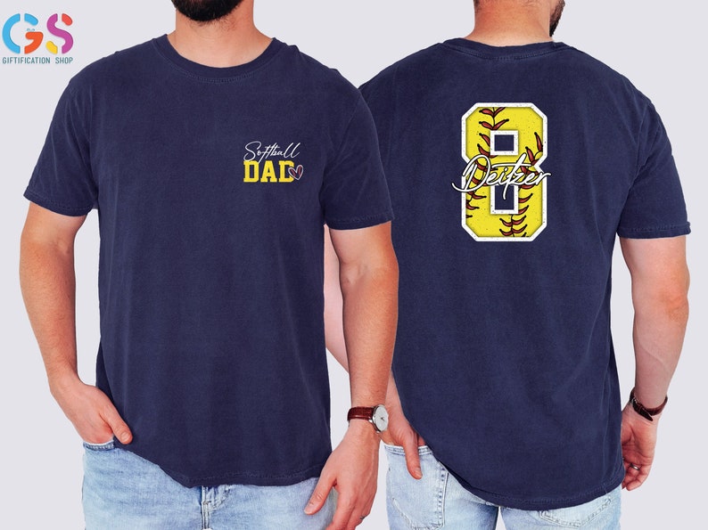 May include: A navy blue t-shirt with the text "Softball Dad" on the front and a yellow softball with the number 8 and the text "Dexter" on the back.