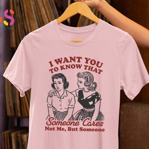 Op de afbeelding: Roze T-shirt met een afbeelding van twee vrouwen. De tekst op het shirt luidt "I want you to know that Someone Cares Not Me, But Someone".
