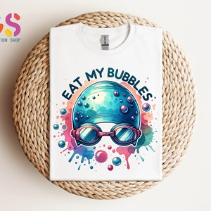 May include: White t-shirt with a colorful watercolor design of a swimming cap and goggles. The text "Eat My Bubbles" is written in a black outline around the design.