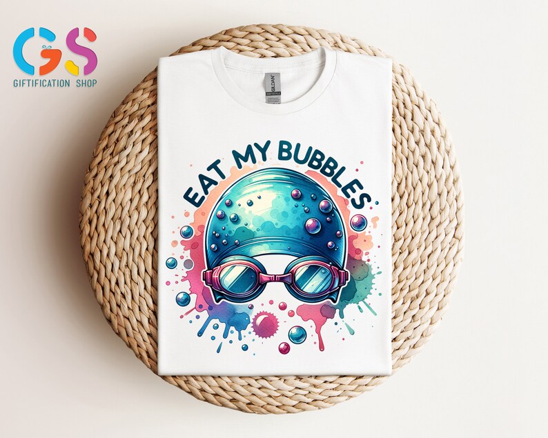 May include: White t-shirt with a colorful watercolor design of a swimming cap and goggles. The text "Eat My Bubbles" is written in a black outline around the design.