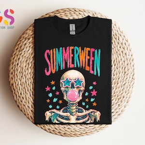 May include: A black t-shirt featuring the text SUMMERWEEN in colorful letters above a graphic of a skeleton wearing star-shaped sunglasses and blowing a pink bubblegum bubble, surrounded by small orange, pink, and teal star accents.