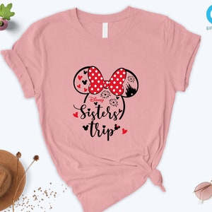 Puede incluir: Camiseta rosa con un dise&ntilde;o de orejas de Mickey Mouse en negro y rojo y el texto "Disney Sisters Trip".