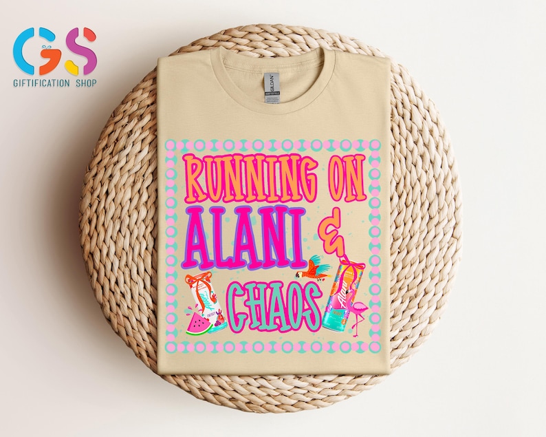 Puede incluir: Una camiseta color beige con las palabras "RUNNING ON ALANI & CHAOS" en rosa, naranja y azul. La camiseta presenta ilustraciones de un loro, un flamenco y una rodaja de sand&iacute;a. La camiseta se muestra sobre una superficie tejida.