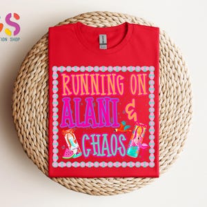 Puede incluir: Una camiseta roja con el texto "RUNNING ON ALANI & CHAOS" en un dise&ntilde;o colorido. El dise&ntilde;o incluye im&aacute;genes de una sand&iacute;a y una bebida. La camiseta se muestra sobre una superficie tejida.