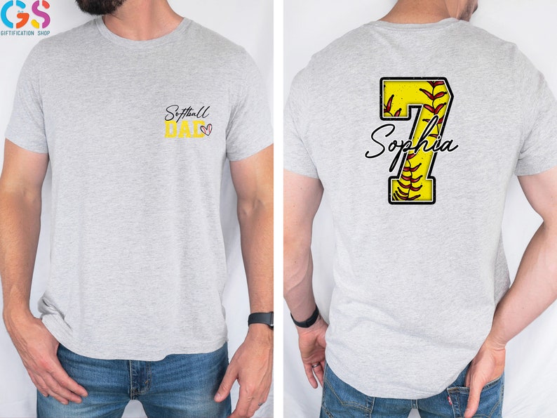May include: A gray t-shirt with the text "Softball Dad" on the front and a yellow softball with the number 7 and the name "Sophia" on the back.
