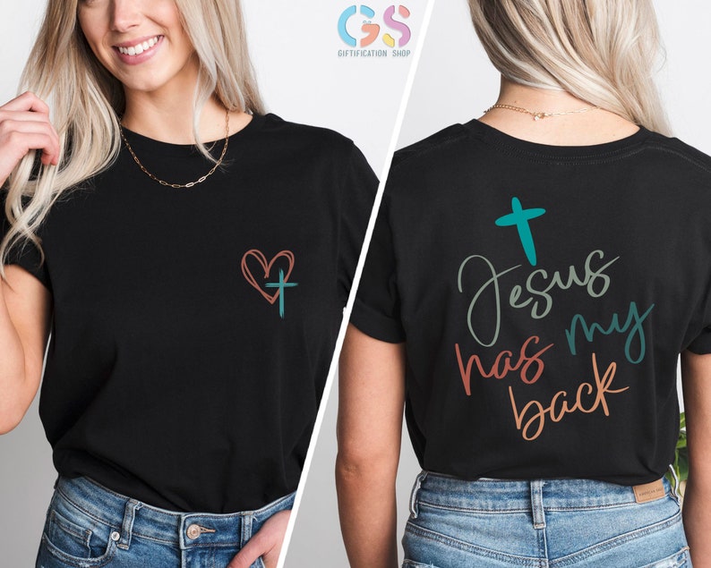 May include: Black t-shirt with a heart and cross on the front and the text "Jesus has my back" on the back. The text is in a colorful, handwritten style.