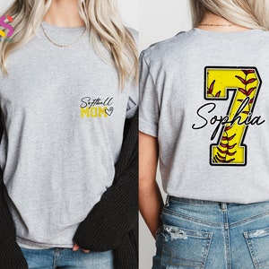 May include: Gray t-shirt with the text "Softball Mom" in yellow on the front and a yellow number 7 with red stitching and the name "Sophia" on the back.