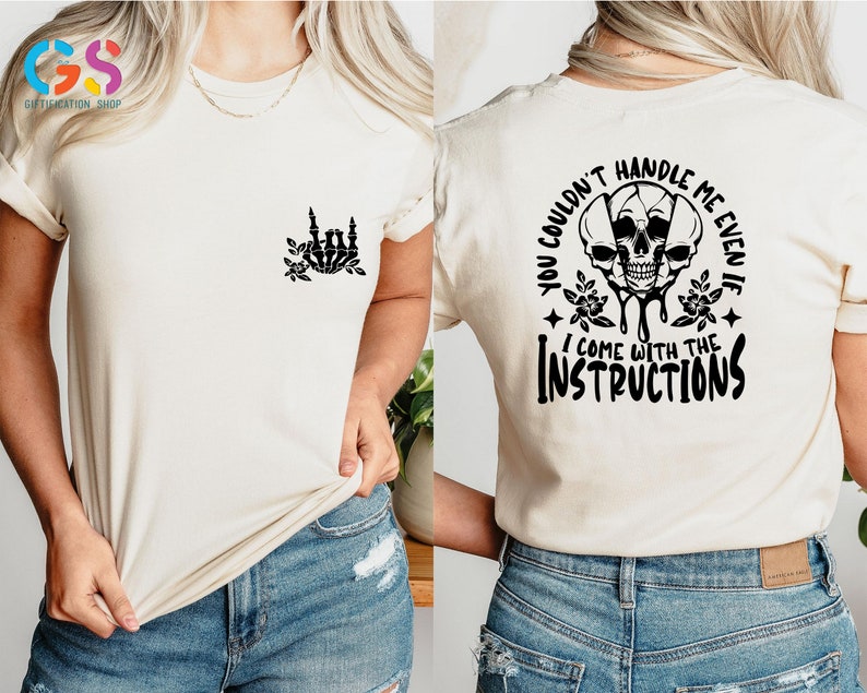 Op de afbeelding: Een wit T-shirt met een zwarte schedelprint en de tekst "You couldn't handle me even if I come with the instructions".