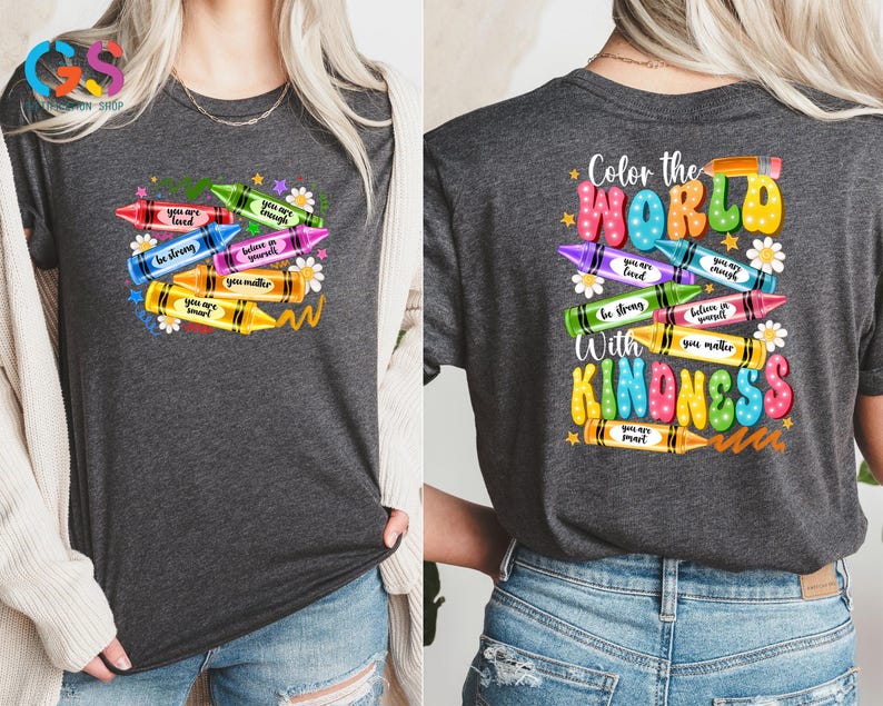 May include: A gray t-shirt with a colorful crayon design. The front of the shirt has a stack of crayons with positive messages written on them. The back of the shirt has the text "Color the World with Kindness" with a similar crayon design.