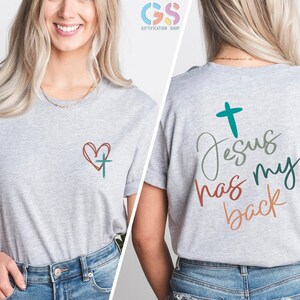 May include: Gray t-shirt with a heart and cross on the front and the text "Jesus has my back" with a cross on the back.