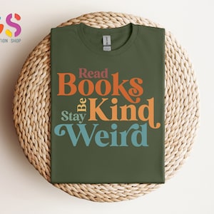 K&ouml;nnte beinhalten: Ein gr&uuml;nes T-Shirt mit dem Text "Read Books Be Kind Stay Weird" in bunter Retro-Schrift.