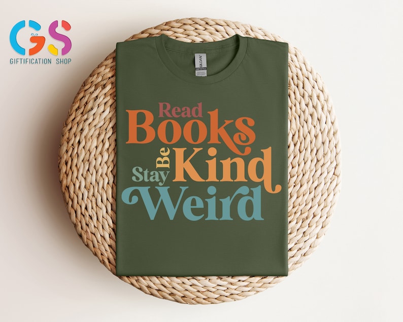 K&ouml;nnte beinhalten: Ein gr&uuml;nes T-Shirt mit dem Text "Read Books Be Kind Stay Weird" in bunter Retro-Schrift.