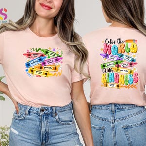 May include: Pink t-shirt with a design of colorful crayons with positive messages like "You are loved", "Be strong", "Believe in yourself", "You matter", and "You are smart". The back of the shirt says "Color the world with kindness" with a similar crayon design.