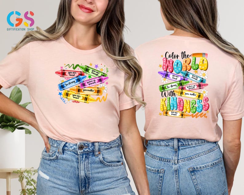 May include: Pink t-shirt with a design of colorful crayons with positive messages like "You are loved", "Be strong", "Believe in yourself", "You matter", and "You are smart". The back of the shirt says "Color the world with kindness" with a similar crayon design.