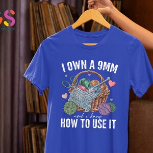 May include: A royal blue t-shirt with the text "I own a 9mm and I know how to use it". The text is white and the shirt features a graphic of a basket of yarn with knitting needles.