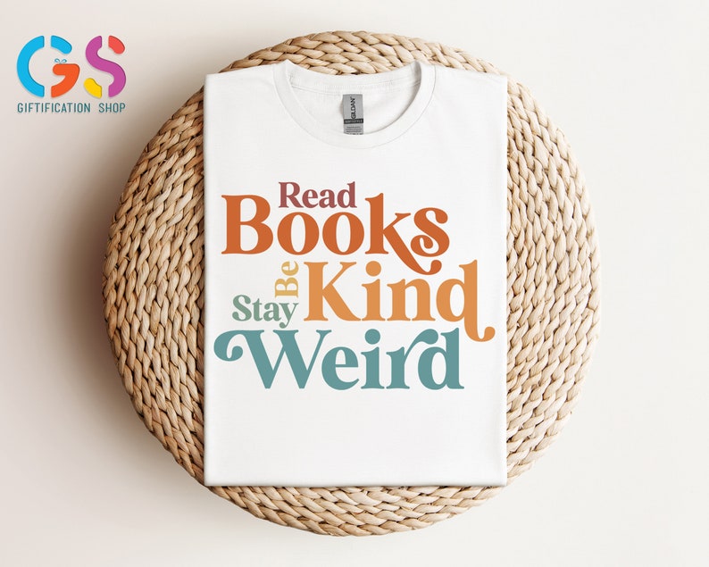 K&ouml;nnte beinhalten: Wei&szlig;es T-Shirt mit dem Text "Read Books Be Kind Stay Weird" in bunter Retro-Schrift.