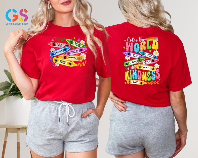 May include: Red t-shirt with a design of colorful crayons with the text "Color the World with Kindness" on the front. The back of the shirt has a design of crayons with positive messages.