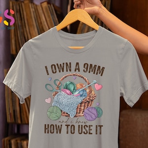 May include: Gray t-shirt with the text "I own a 9mm and I know how to use it". The shirt features a basket with yarn and knitting needles.