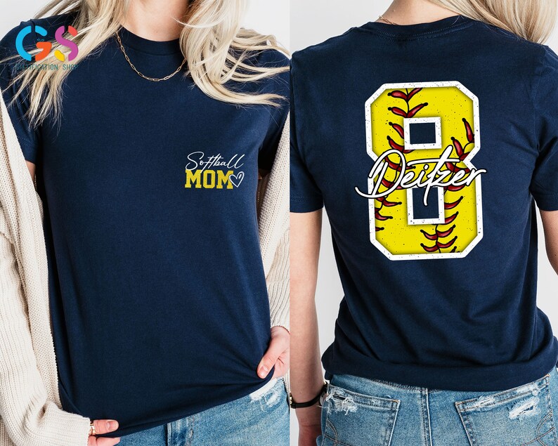May include: Two navy blue t-shirts. The front of one shirt says "Softball Mom" with a heart. The back of the other shirt has a yellow softball with red stitching and the number 8 with the name "Deitzer" written in white.