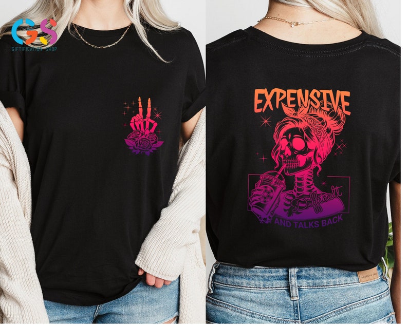 May include: Black t-shirt with a pink and orange gradient design. The front of the shirt features a skeleton hand making a peace sign with roses. The back of the shirt features a skeleton woman with a skull head drinking from a cup. The text "Expensive and Talks Back" is printed below the image.