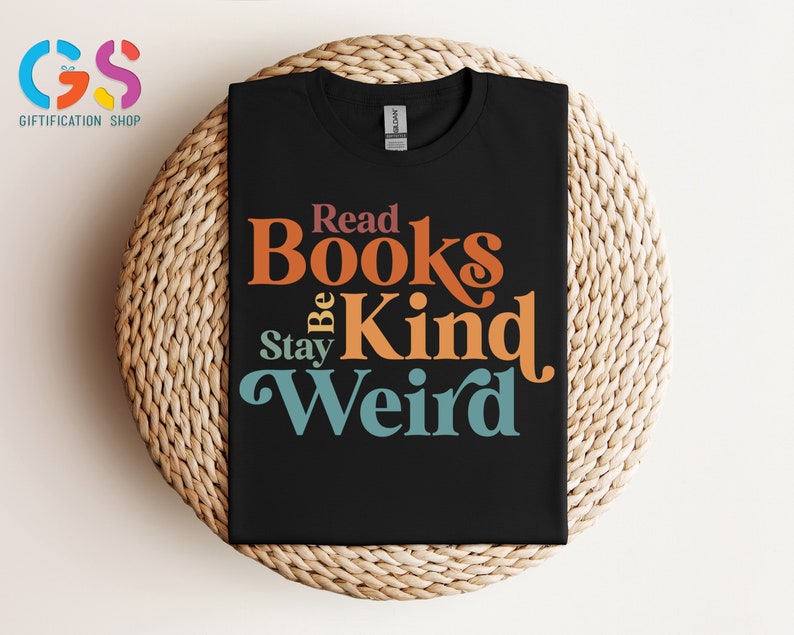 K&ouml;nnte beinhalten: Schwarzes T-Shirt mit einer Retro-Grafik, auf der "Read Books Be Kind Stay Weird" steht. Der Text ist in verschiedenen Farben gehalten, darunter Orange, Rot, Blau und Gr&uuml;n.