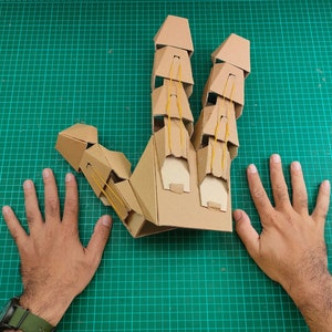 Cardboard Articulated mechanical finger claw compared with adult hand size
