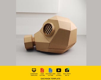 Könnte beinhalten: Eine braune Gasmaskenvorlage aus Pappe mit geometrischem, facettiertem Design, einem runden Filtergehäuse und einem geschlitzten runden Sichtfenster. Das untere gelbe Banner enthält Symbole für Pappvorlagen, PDF, SVG, Video und echtes Handwerk.