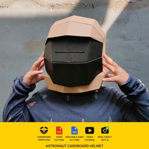 Op de afbeelding: Een beige kartonnen astronautenhelm met een zwart vizier voorzien van een horizontale gleuf. De gele banner onderaan toont iconen voor kartonnen sjablonen, PDF, SVG, video-tutorial en echt handwerk, met de tekst ASTRONAUT CARDBOARD HELMET.