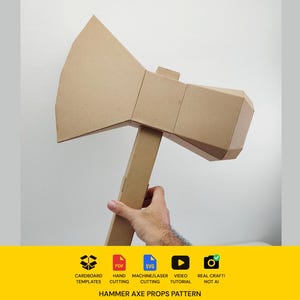 Pode incluir: Um acessório de machado de papelão com uma lâmina grande e angular e uma cabeça retangular presa a um cabo longo. Abaixo do objeto, uma faixa amarela exibe o texto: CARDBOARD TEMPLATES, PDF, SVG, HAND CUTTING, MACHINE/LASER CUTTING, VIDEO TUTORIAL, REAL CRAFT! NOT AI, HAMMER AXE PROPS PATTERN.