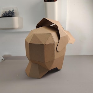 May include: A geometric, brown cardboard sculpture of a dog's head and body. The sculpture is made of folded cardboard pieces, creating a faceted appearance. The dog's head has a flap that serves as an ear.