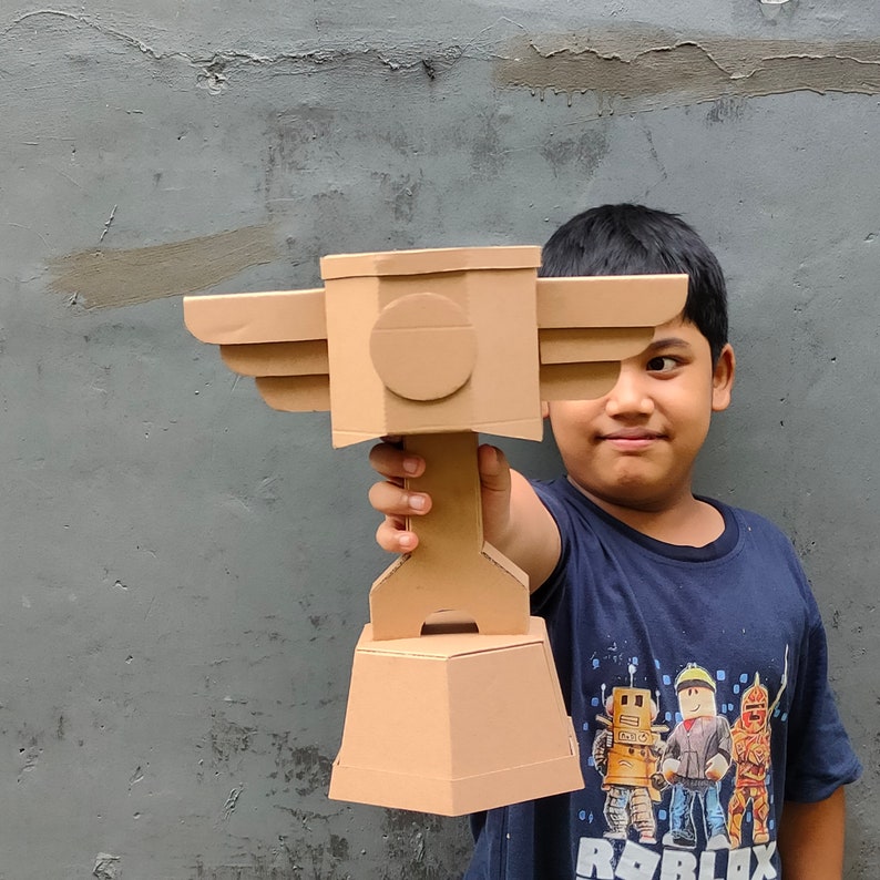 Cardboard Trophy Cup for Racing with a piston and wings held by kid