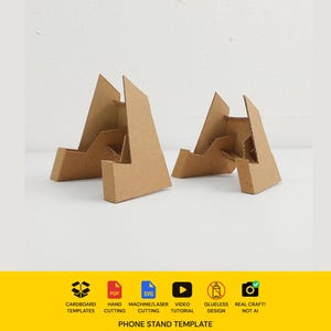 Può includere: Due supporti per telefono in cartone marrone dal design angolare e geometrico. Sotto i supporti, una fascia gialla mostra icone per modelli in cartone, PDF, SVG, tutorial video, design senza colla e artigianato, con il testo PHONE STAND TEMPLATE.