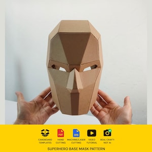May include: A tan cardboard superhero base mask pattern with a geometric, faceted design featuring angular eye cutouts and a pointed nose section. The bottom yellow banner displays icons for cardboard templates, PDF, SVG, video tutorial, and real craft.