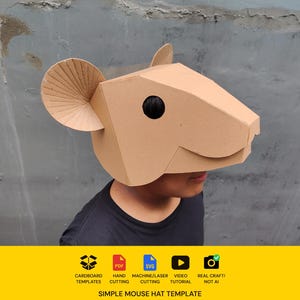 May include: A tan cardboard mouse mask featuring large circular ears with ribbed detailing and a dark circular eye cutout. The bottom section includes text icons for cardboard templates, PDF, SVG, video tutorial, and real craft, plus the text Simple Mouse Hat Template.
