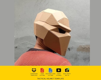 Könnte beinhalten: Ein geometrischer Helm im Low-Poly-Stil aus beigefarbener Pappe. Der Helm hat ein facettiertes, kantiges Design mit einer einzelnen horizontalen Augenöffnung. Unter dem Helm steht der Text: CARDBOARD TEMPLATES, PDF, SVG, HAND CUTTING, MACHINE/LASER CUTTING, VIDEO TUTORIAL, REAL CRAFT! NOT AI, TACTICAL HELMET TEMPLATE.