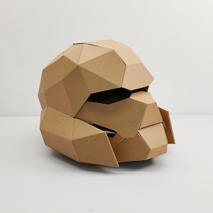Plantilla de casco de tropa de ciencia ficción de cartón con cara de calavera robótica. Patrón imprimible DIY para crear un casco de robot a partir de cartón corrugado.