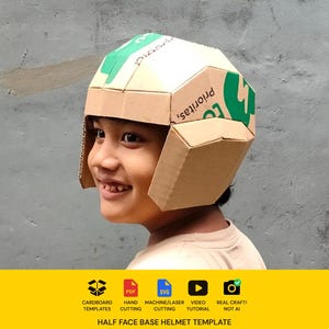 Puede incluir: Un casco de cartón construido con embalajes reciclados con marcas y texto en verde visibles. El casco presenta un diseño geométrico de varios paneles con protectores laterales. Una franja amarilla muestra iconos para plantillas de cartón, PDF, SVG, corte láser, tutorial en vídeo y artesanía real, con el texto Half Face Base Helmet Template.