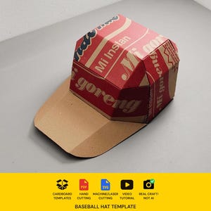 May include: A baseball hat constructed from cardboard featuring red and tan panels with the printed text Mi Instan and Mi goreng. The design includes a structured crown and a flat brim, showcasing a template for a paper craft project.