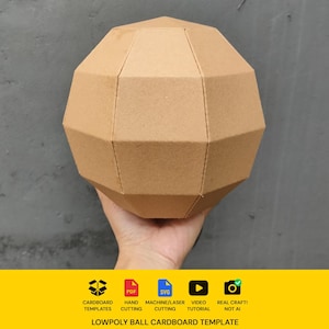 Op de afbeelding: Een beige kartonnen low-poly bal met geometrische facetten. Onder de bal toont een gele banner iconen voor kartonnen sjablonen, PDF, SVG, handmatig snijden, machine/lasersnijden, video-tutorial en echt ambacht, met de tekst: LOWPOLY BALL CARDBOARD TEMPLATE.