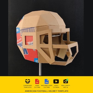 Peut inclure: Un casque de football américain géométrique fabriqué en carton brun. Le panneau latéral présente des graphismes imprimés en rouge et bleu avec un code-barres. Le casque comprend une grille de protection rigide et une structure en dôme facetté.